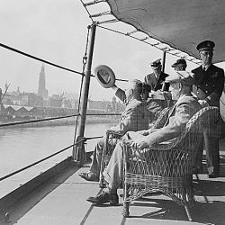 President Harry S. Truman acknowledges cheers from the crowd on the Antwerp docks as the U. S. S. Augusta enters Belgian waters. Press Secretary Charles Ross is seated in foreground. Adm. William Leah