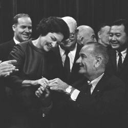 Photograph of President Lyndon B. Johnson handing Lady Bird Johnson a signing pen at the signing ceremony for the Highway Beautification Act