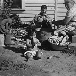 Family husking corn on the porch