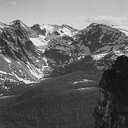 View of snow-capped mountain timbered area below, "In Rocky Mountain National Park," Colorado. (Vertical Orientation)