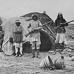Apache rancheria with two men holding rifles
