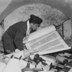 In the cellar of the Race Institute in Frankfurt, Germany, Chaplain Samuel Blinder examines one of hundreds of "Saphor Torahs" (Sacred Scrolls), among the books stolen from every occupied country in E