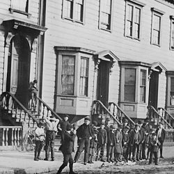 Children play ball in the street in front of typical housing with five rooms per family for $10 to $12 per month. San Francisco