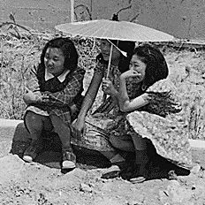 Stockton, California. These evacuees of Japanese ancestry are watching the arrival of buses bringing. . .