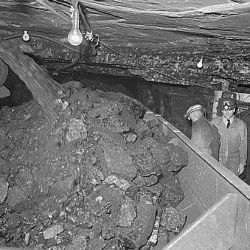 Rear Admiral Joel T. Boone, on inspection trip of Southern Illinois and Indiana mines, watches loading of coal into shuttle cars by conveyor belt. Consolidated Coal Company, Lake Creek Mine, Johnson C