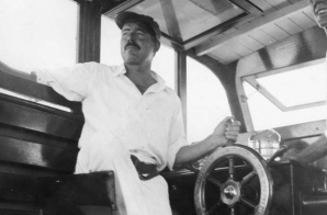 Ernest Hemingway at the wheel of his boat, Pilar, with Carlos Gutierrez.