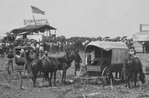 Anadarko Townsite, August 8, 1901. Auction in progress in lumber company booth. Temporary bank buildings and the beginnings of a lodging house nearby