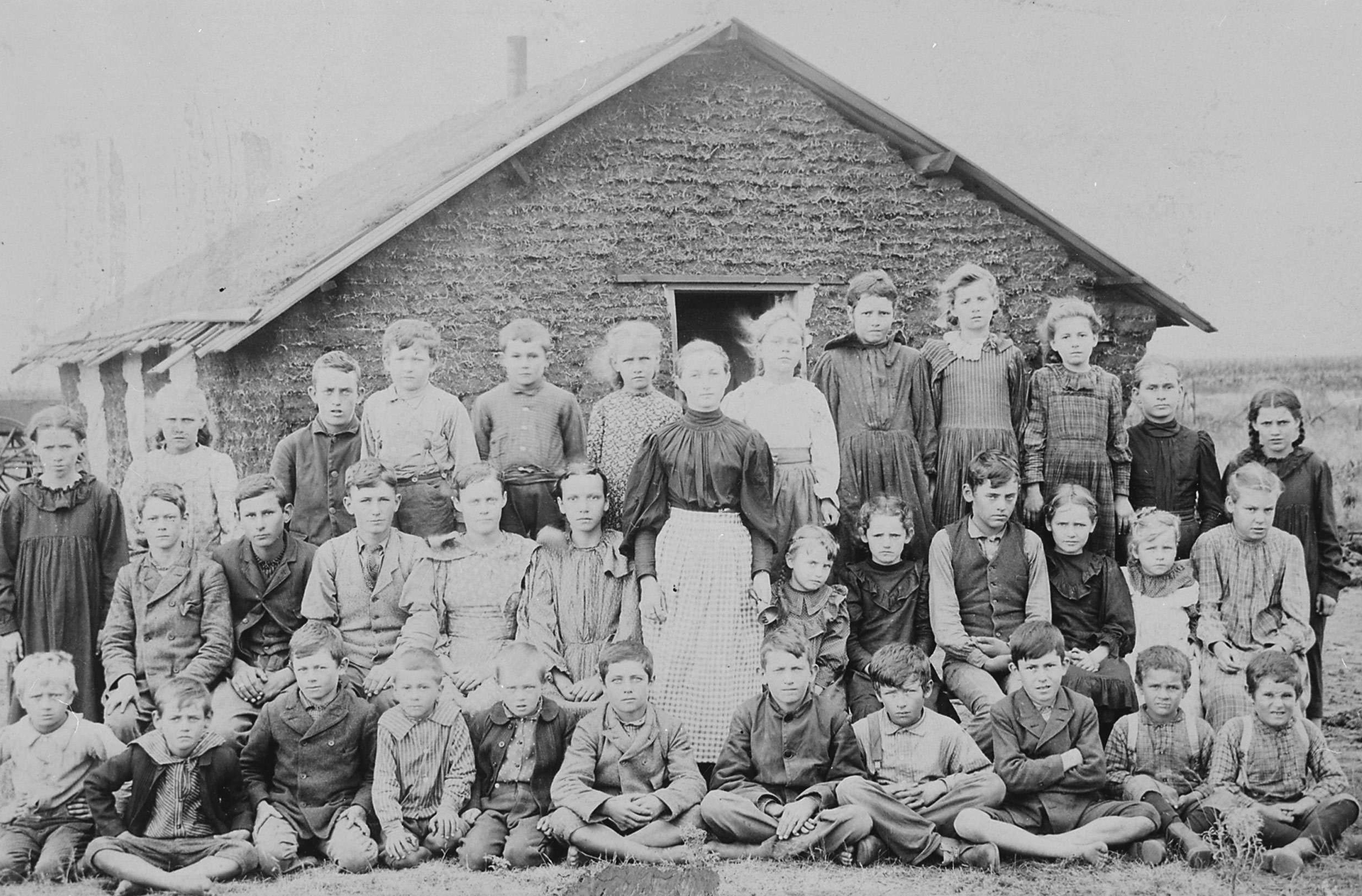 Teacher and Children in Front of Schoolhouse