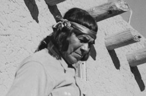 Indian descending wooden stairs with drum, another in background looking on, "Dance, San Ildefonso Pueblo, New Mexico, 1942