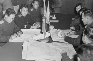 Colonel James Murray, Jr., USMC, and Colonel Chang Chun San, of the North Korean Communist Army, initial maps showing the north and south boundaries of the demarcation zone, during the Panmunjom cease